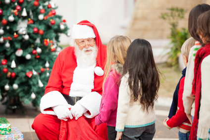 Santa Claus looking at children standing in a queue outdoors