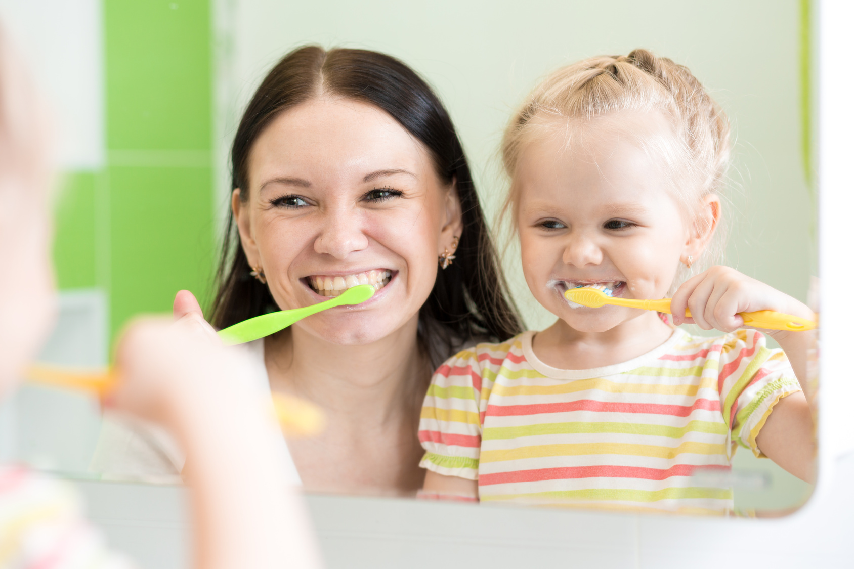 Hygiene. Happy mother and child girl brushing teeth together